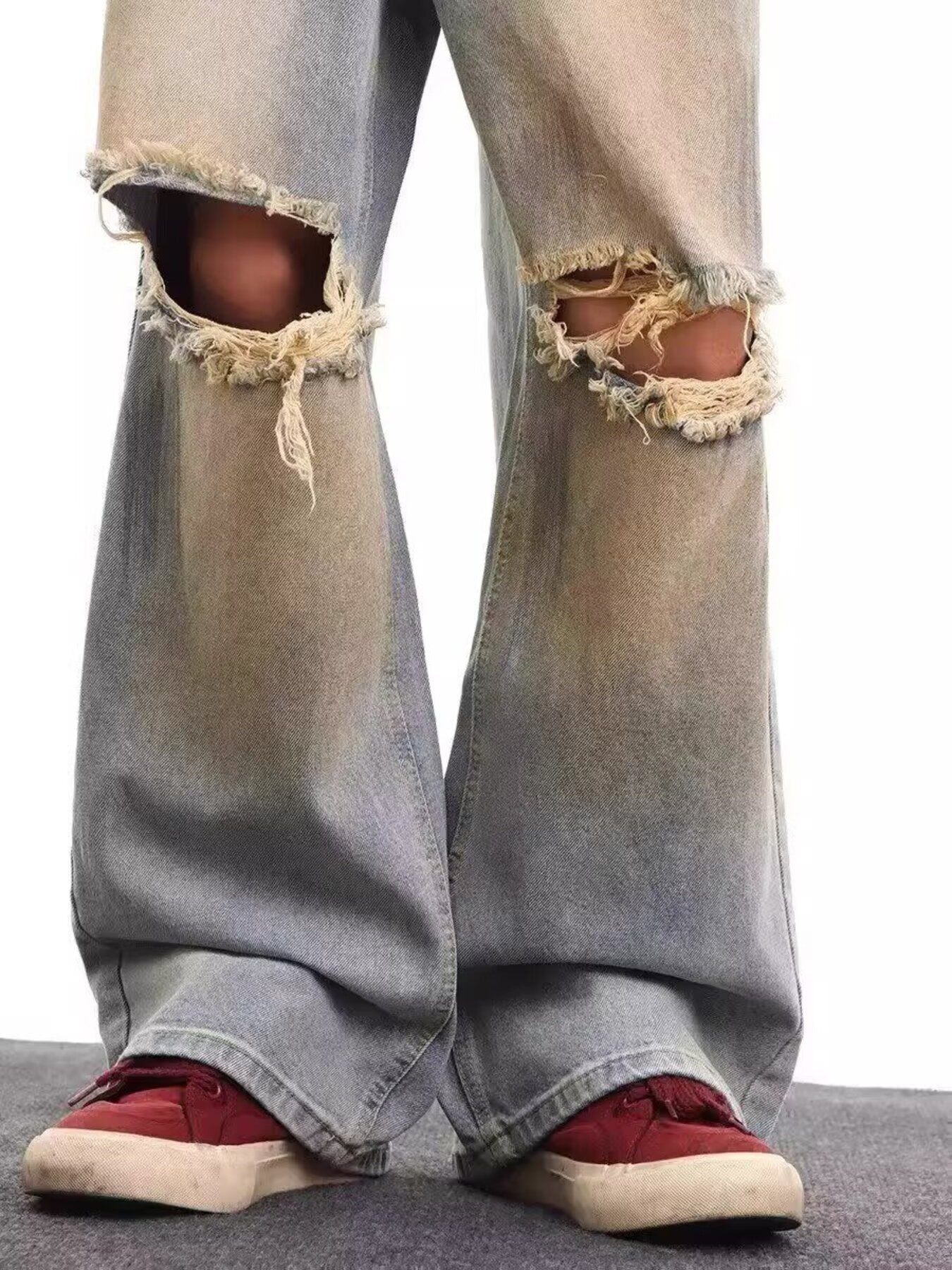 Men's light blue distressed wide leg jeans with frayed knee rips.