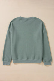 Relaxed crewneck sweater in sage waffle knit cotton with long sleeves and ribbed cuffs and hem.