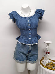 Blue ruffled smocked maternity blouse with puff sleeves, lace trim, and decorative buttons.