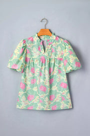 Pastel floral print polyester blouse with ruffled neckline and puff sleeves.