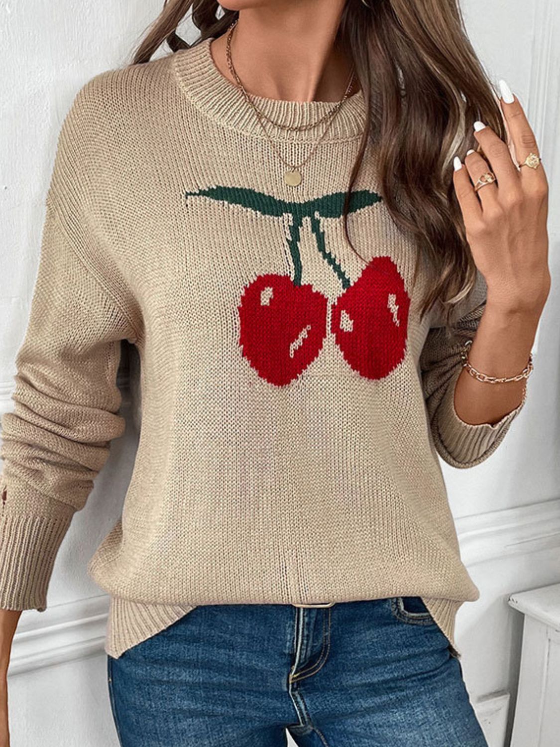 Khaki knit jumper with a red cherry motif, crewneck, and long sleeves.