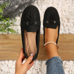 Black suede loafer flats with tassel detail and metal eyelets.