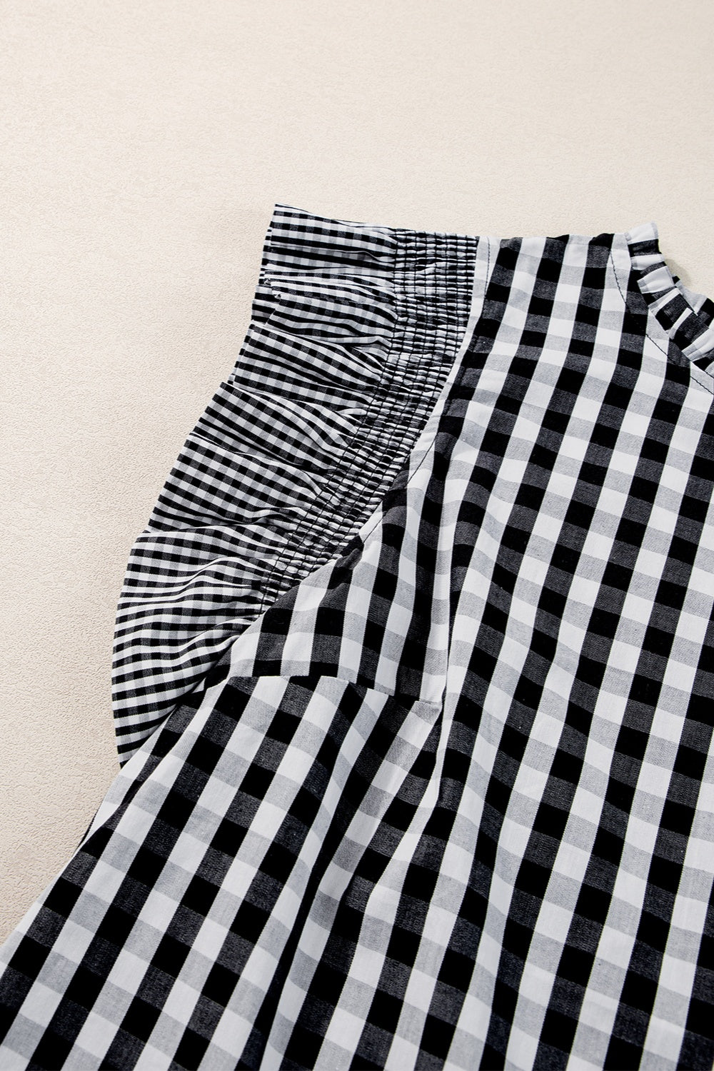 Black gingham blouse with ruffled mock neck and ruffle sleeves.