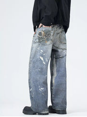 Men's wide-leg jeans in dusty blue denim with paint splatters and chain detail.