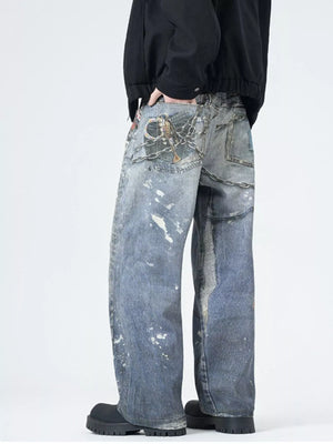 Men's wide-leg jeans in dusty blue denim with paint splatters and chain detail.