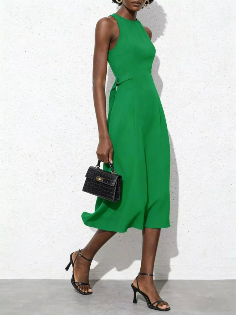 Green midi dress with tie waist, sleeveless, A-line skirt, and a black croc-embossed handbag.