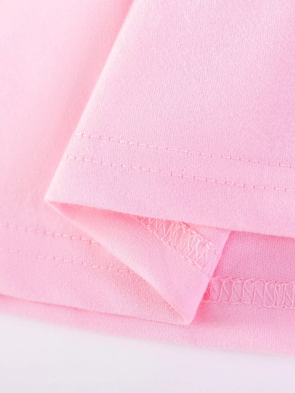 Pink cotton baby dress detail showing seams and fabric texture.
