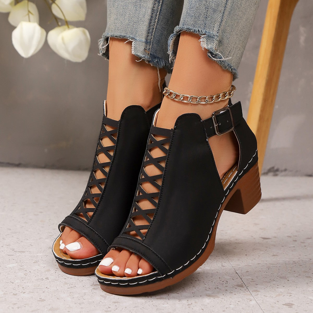 Black criss-cross cut-out block heel sandals with ankle strap and buckle closure.