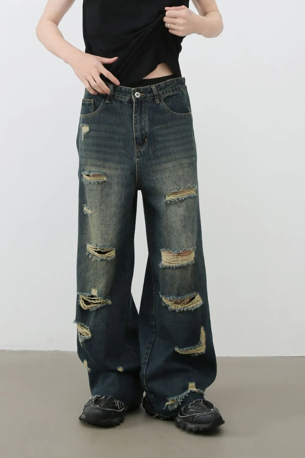 Distressed dark wide leg denim jeans with ripped details and side slits.