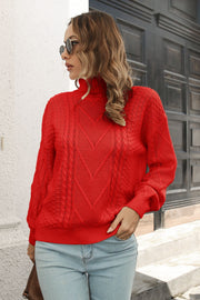 Red acrylic cable knit turtleneck sweater with chevron pattern and long sleeves.