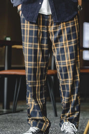 Men's relaxed fit sweatpants in black and mustard plaid with elastic waist.