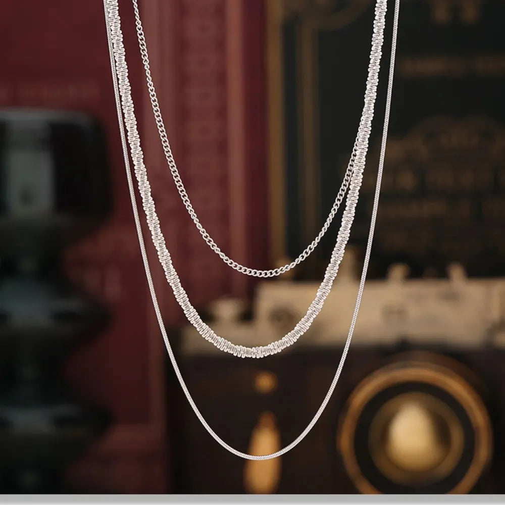 Delicate three-strand silver necklace with crystal accents and chain details