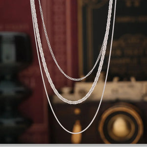Delicate three-strand silver necklace with crystal accents and chain details