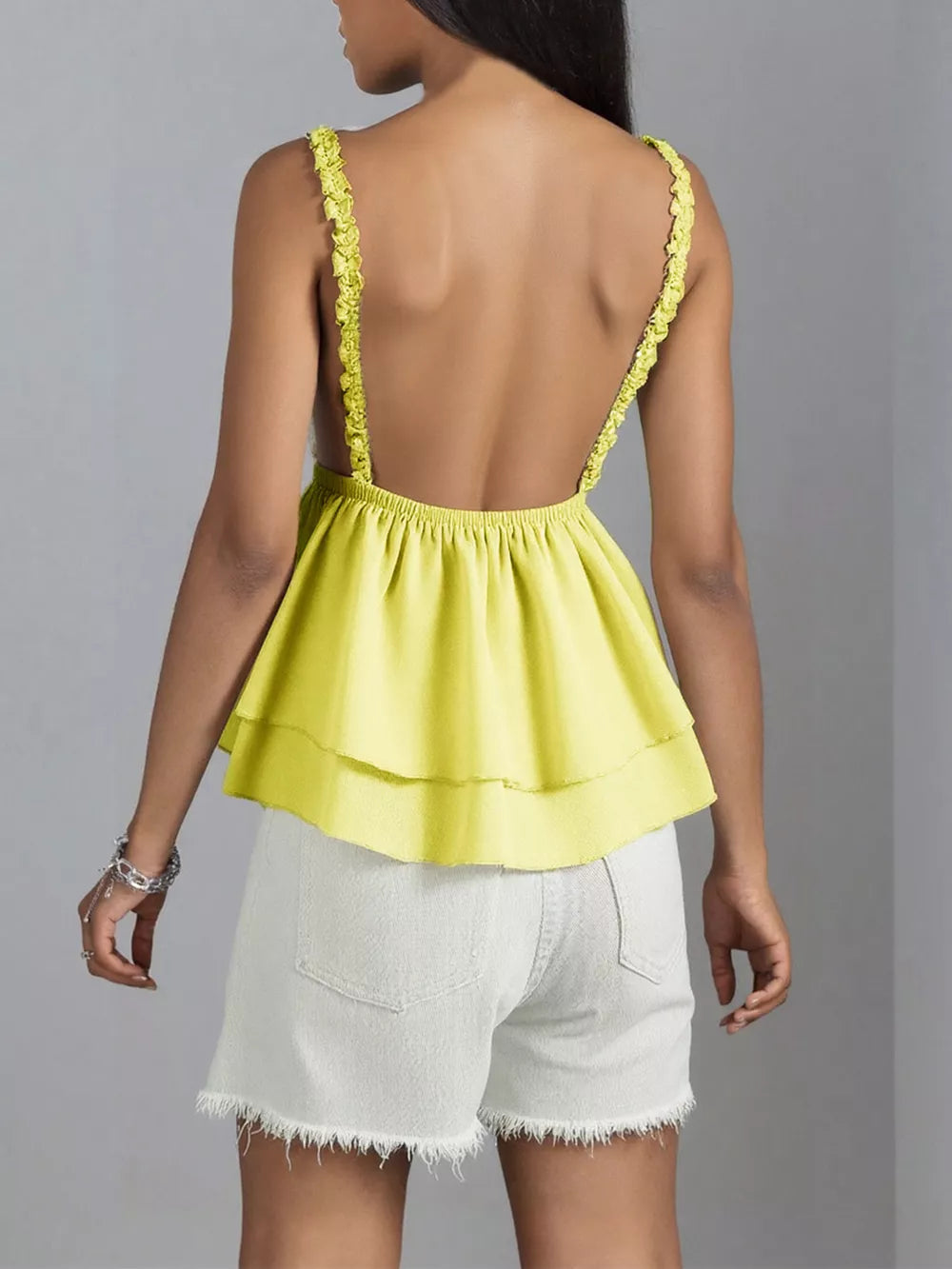 Light yellow camisole with lace trim straps and a tiered peplum hem.