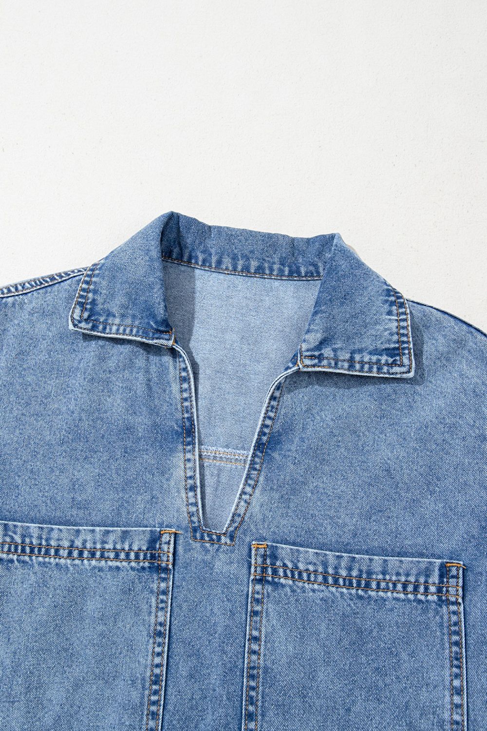 Light blue denim mini dress with collar, V-neck, and two chest pockets.