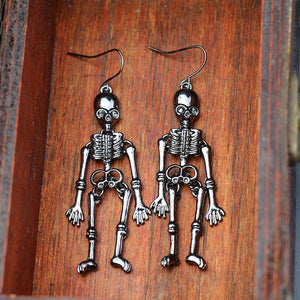 Skeleton silhouette drop earrings in black alloy with articulated limbs and intricate bone detail.