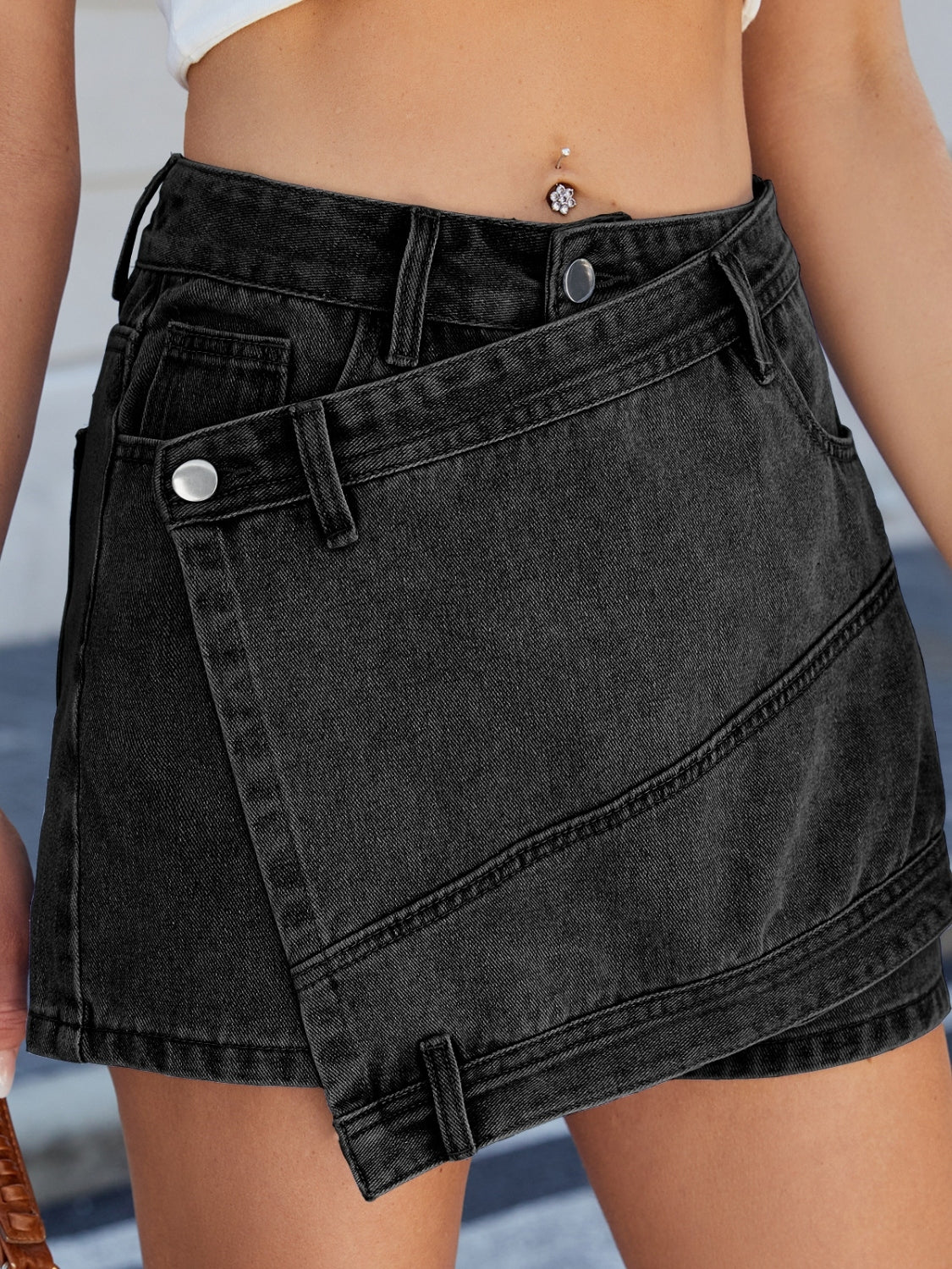 Black denim skort with wrap-effect front and angled seams.