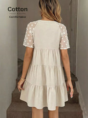 Tiered mini dress in beige cotton with sheer dot sleeves and a ruffled hem.