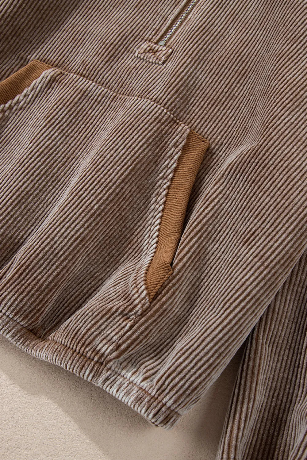 Brown corduroy pullover hoodie with quarter zip and pocket detail.