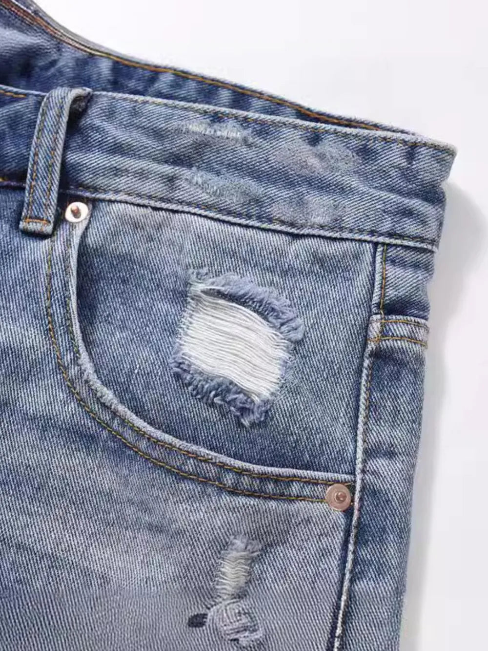 Ripped denim bermuda shorts in medium wash with distressed details and frayed edges.
