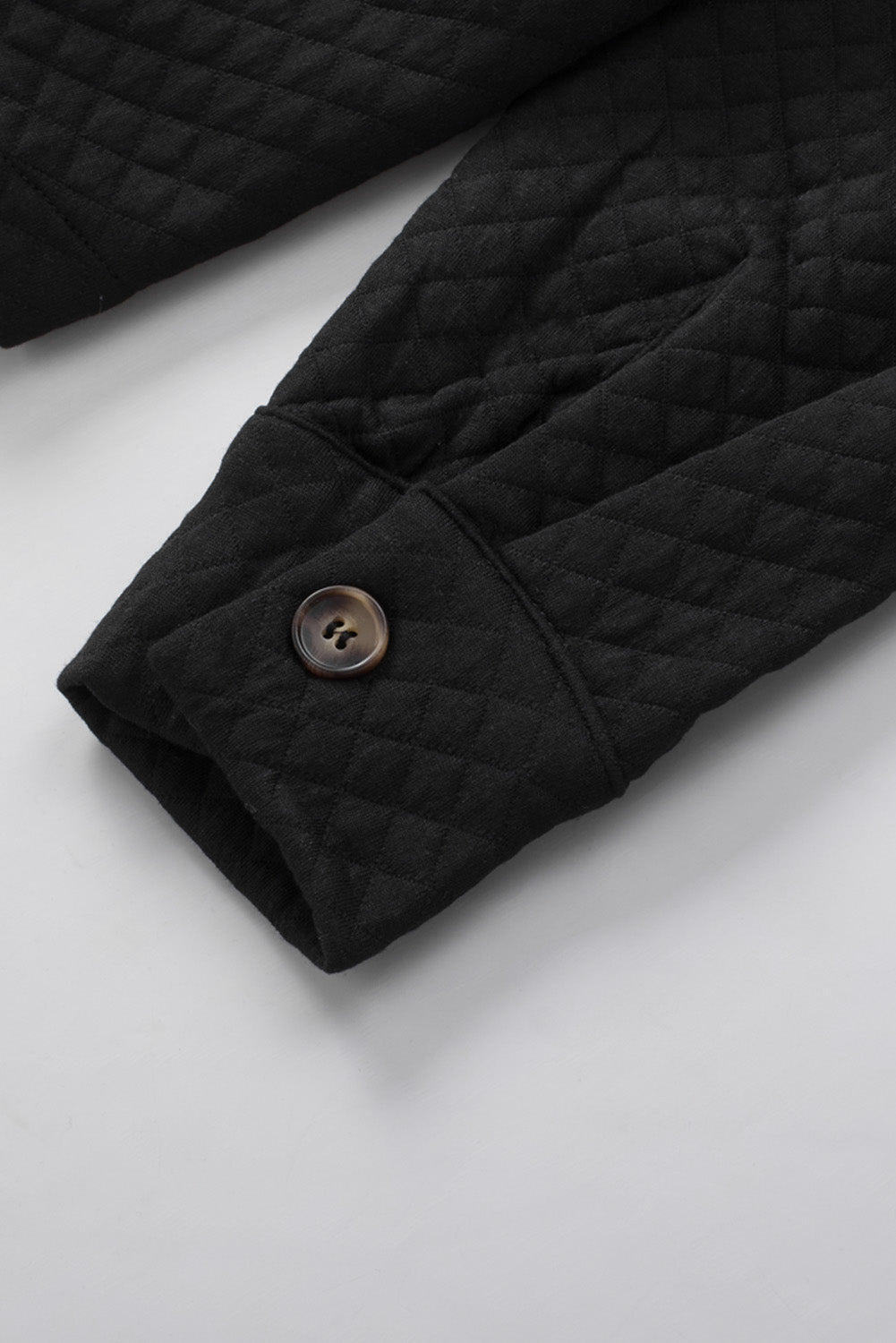 Black quilted overshirt detail showing diamond pattern and button cuff