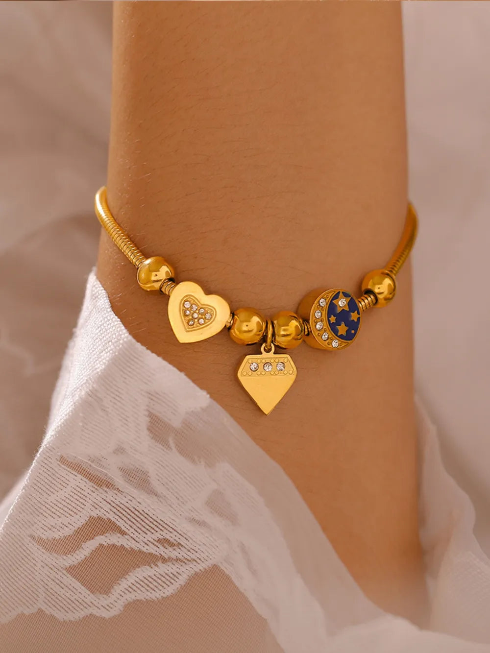 Gold celestial charm bracelet with diamond heart, diamond, and moon charms.
