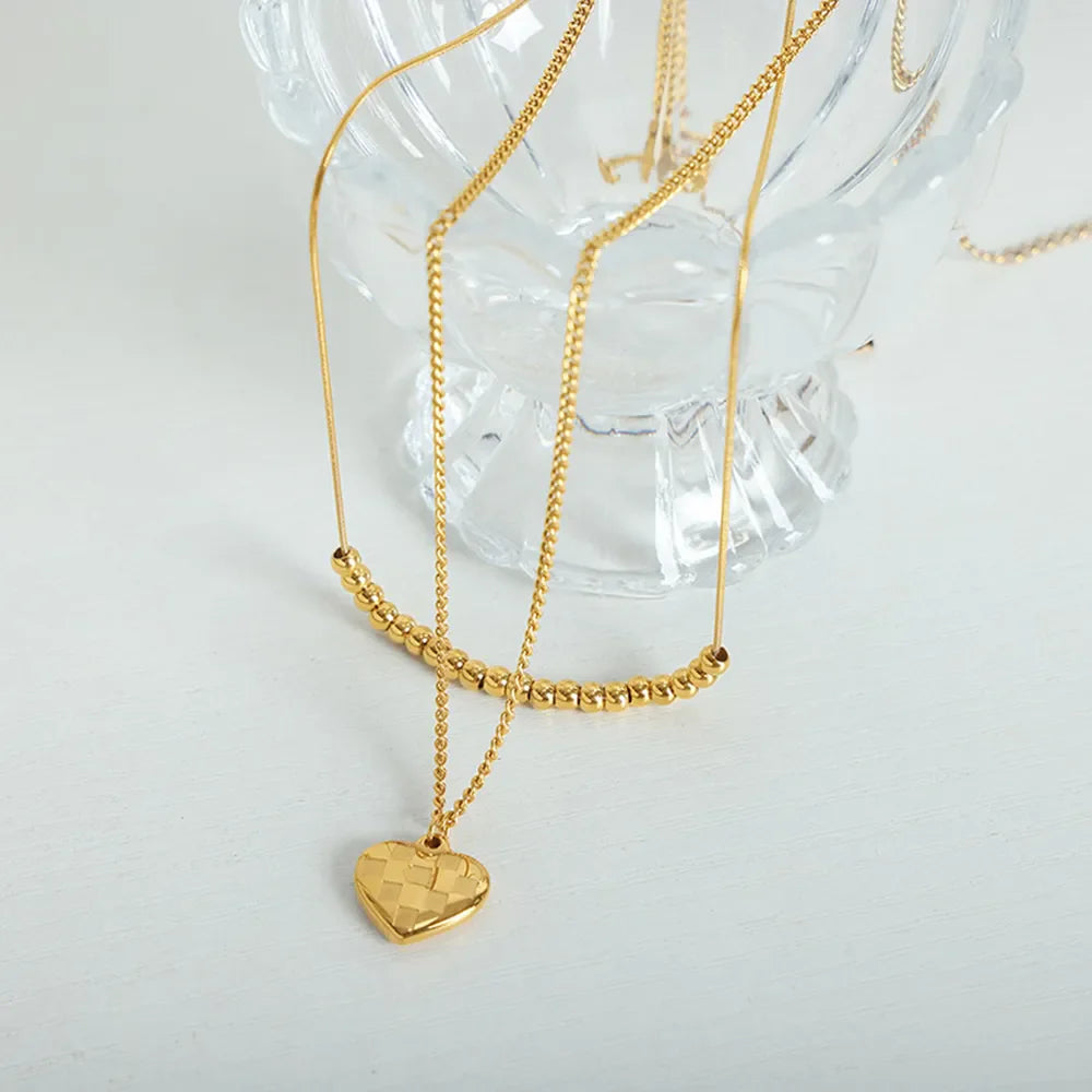 Gold layered necklace with beaded bar and checkered heart charm