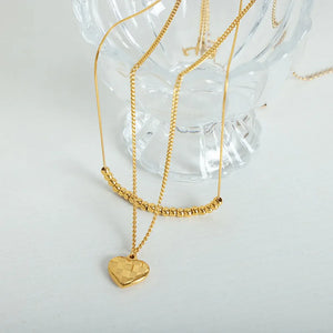 Gold layered necklace with beaded bar and checkered heart charm