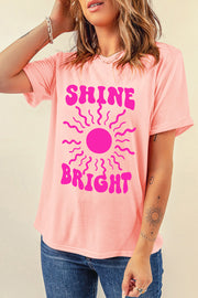 Watermelon pink t-shirt with a retro sunburst graphic and "Shine Bright" text.