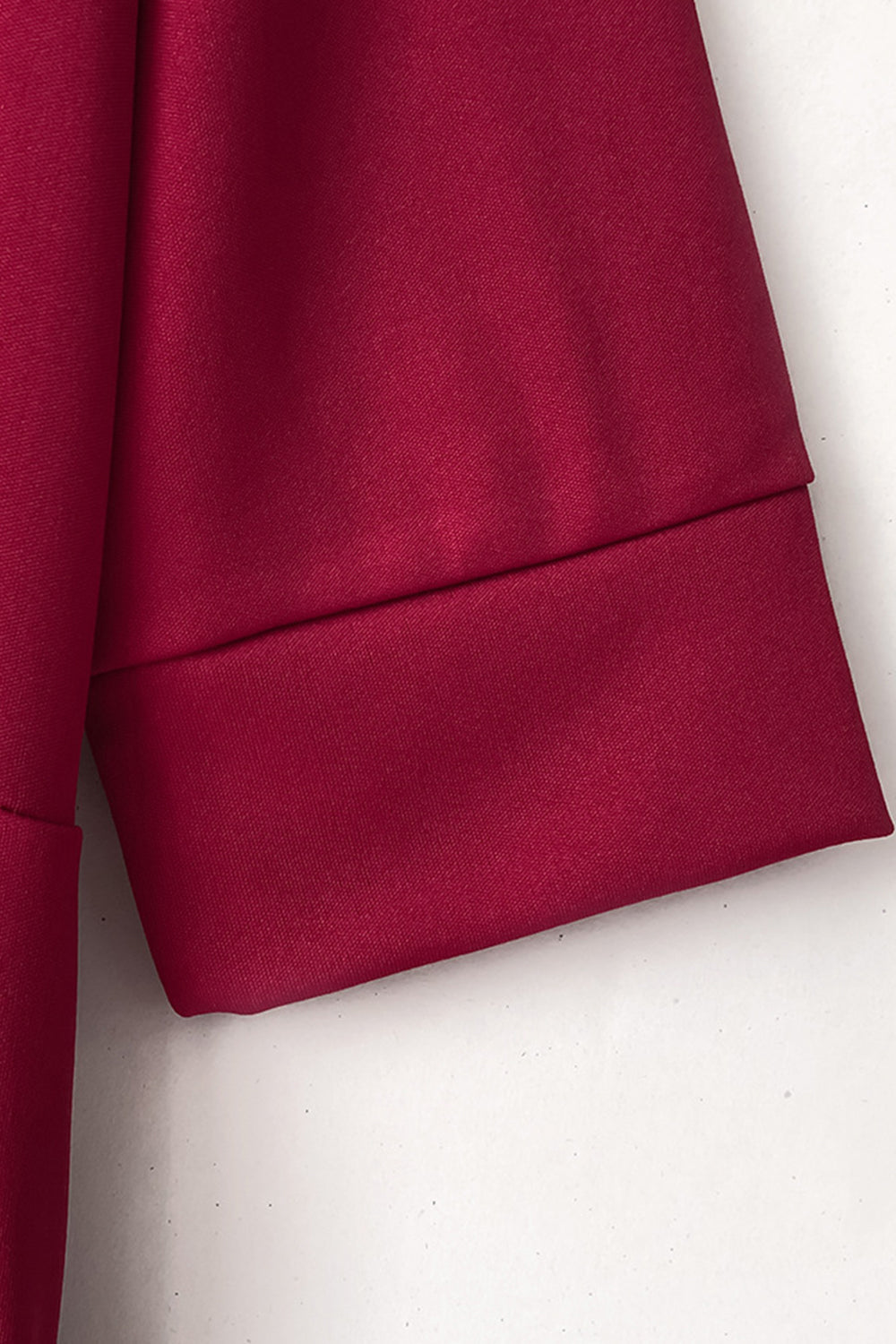 Burgundy jumpsuit with cuffed sleeves and belt detail.