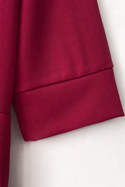 Burgundy jumpsuit with cuffed sleeves and belt detail.