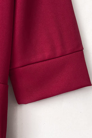 Burgundy jumpsuit with cuffed sleeves and belt detail.