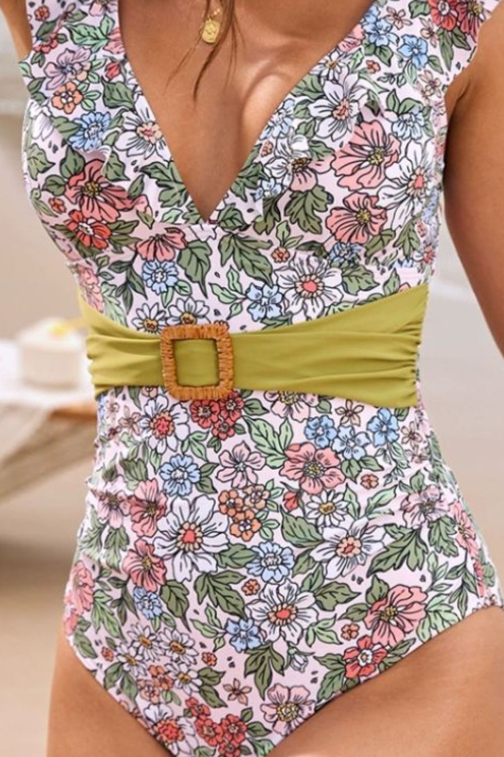 Belted floral plunge swimsuit with a green sash and square buckle detail.