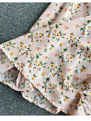Pink floral midi dress with ruffled hem and belted waist detail.