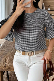 Black and white gingham polyester shirt with ruffled sleeves and a round neckline.