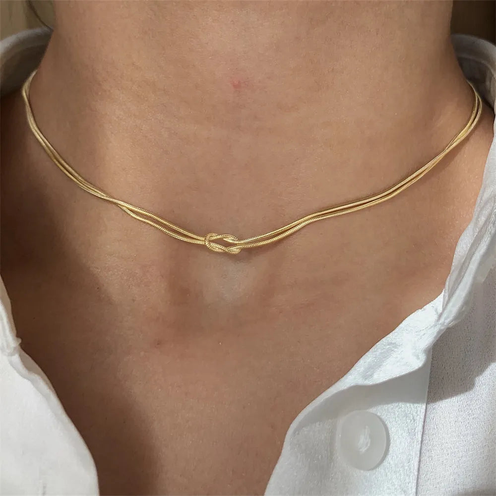 Gold serpent knot necklace with two delicate chains.