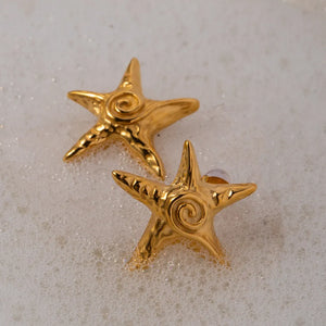 Golden starfish stud earrings with a textured finish and spiral detail.