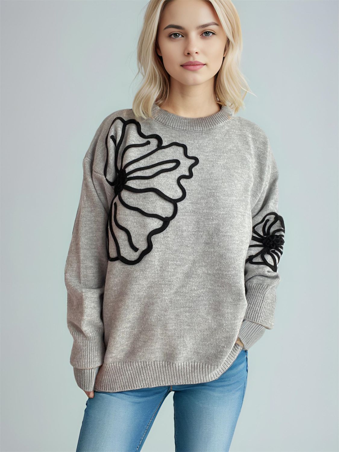 Gray knit sweater with black floral applique on chest and sleeve, crew neck, long sleeves.