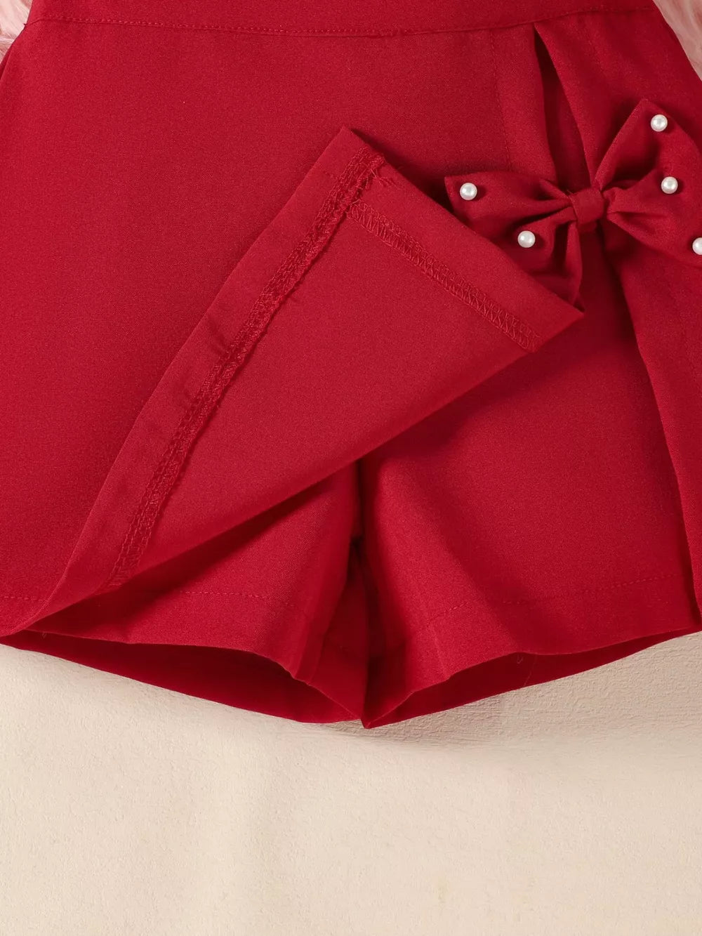 Wine red baby skort with pearl-embellished bow detail.