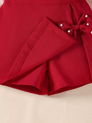 Wine red baby skort with pearl-embellished bow detail.