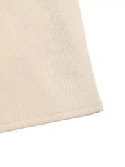 Cream pleated V-neck strapless romper detail showing textured fabric and hem.