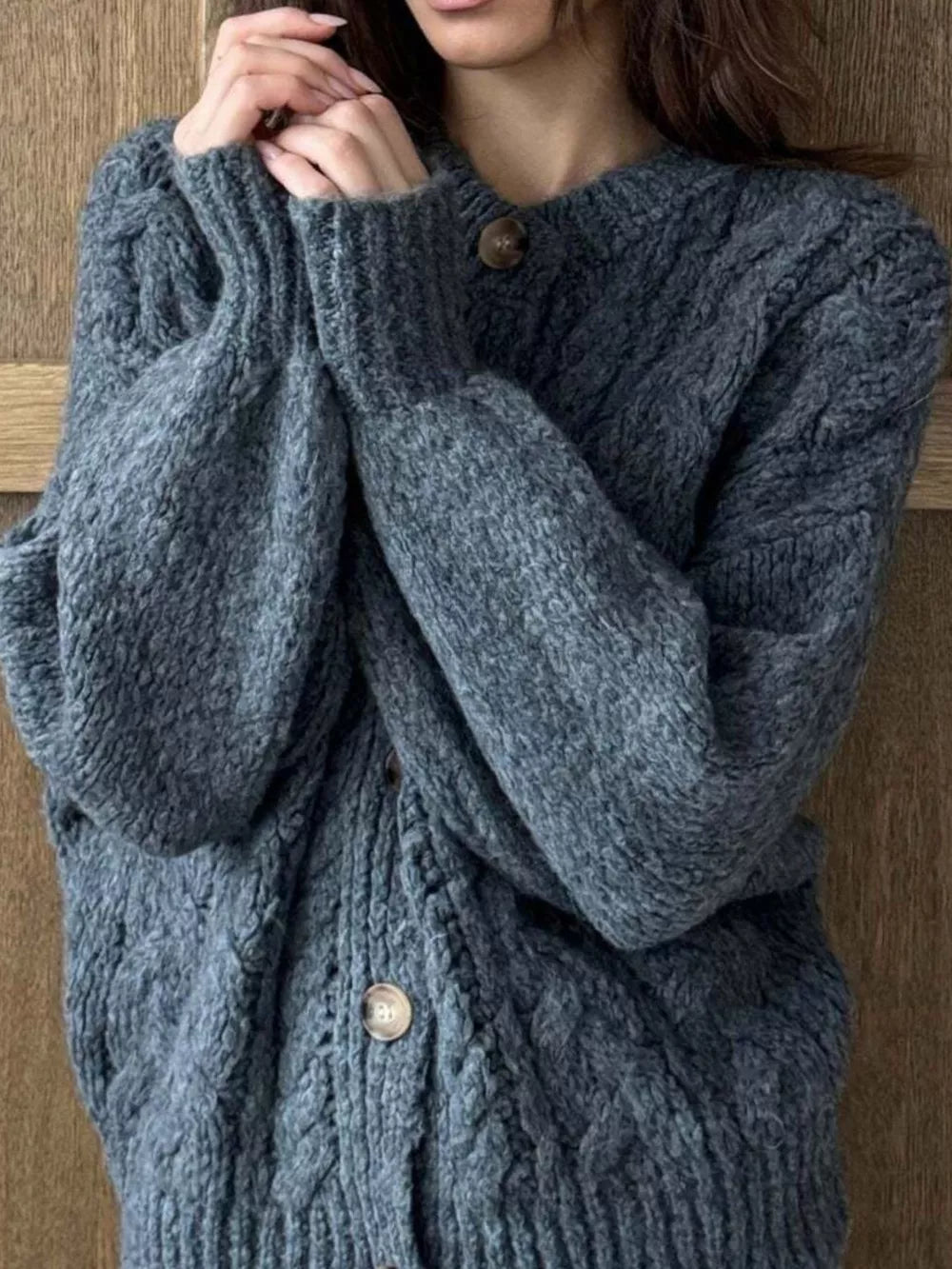 Gray cable-knit button-down cardigan with round neckline and wooden buttons.