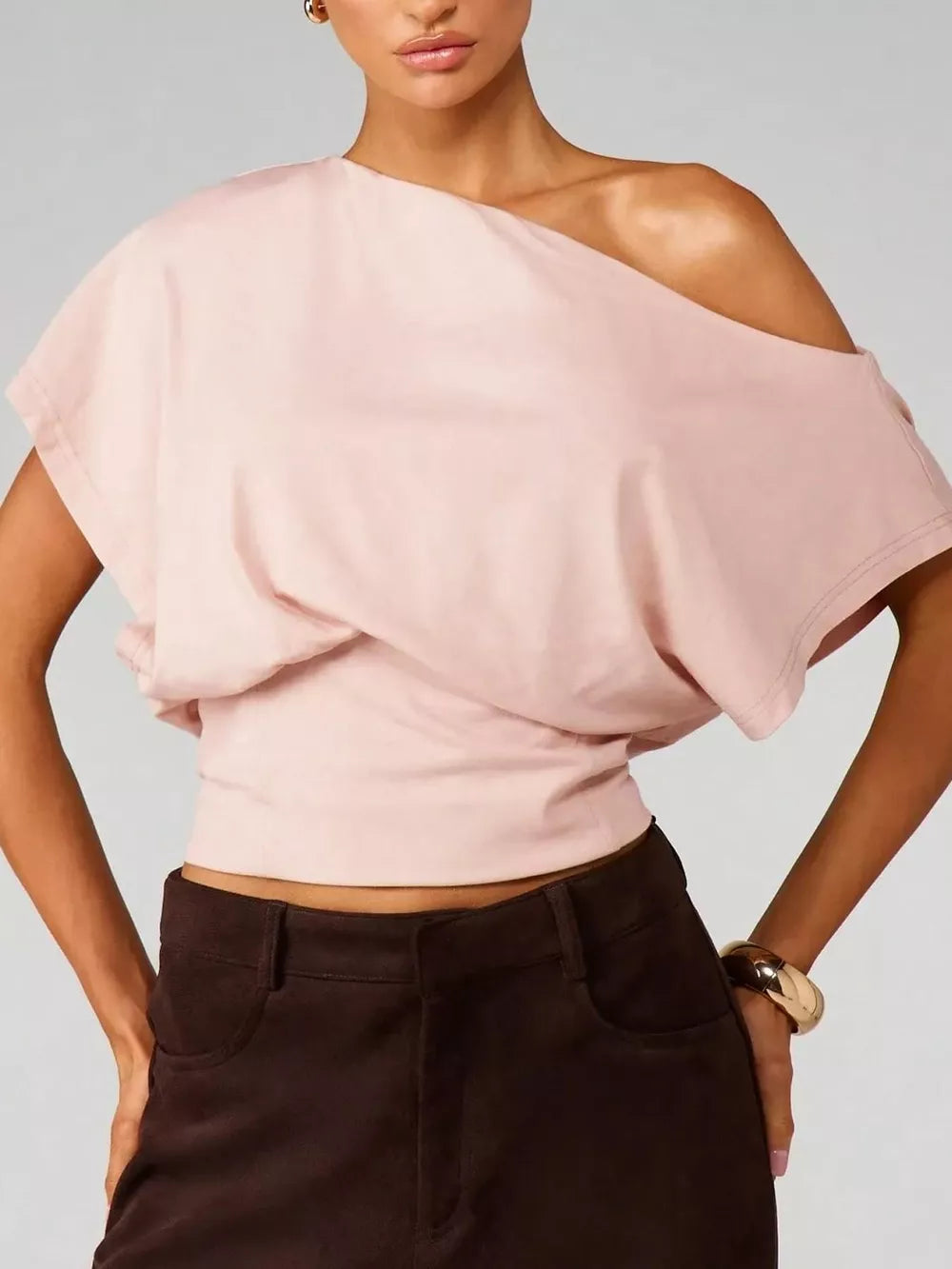 Pink asymmetrical crop t-shirt with draped fit and off-the-shoulder neckline.