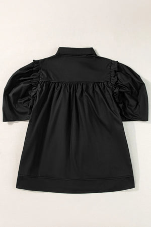 Black poplin blouse with gathered sleeves and ruffled shoulder detail.