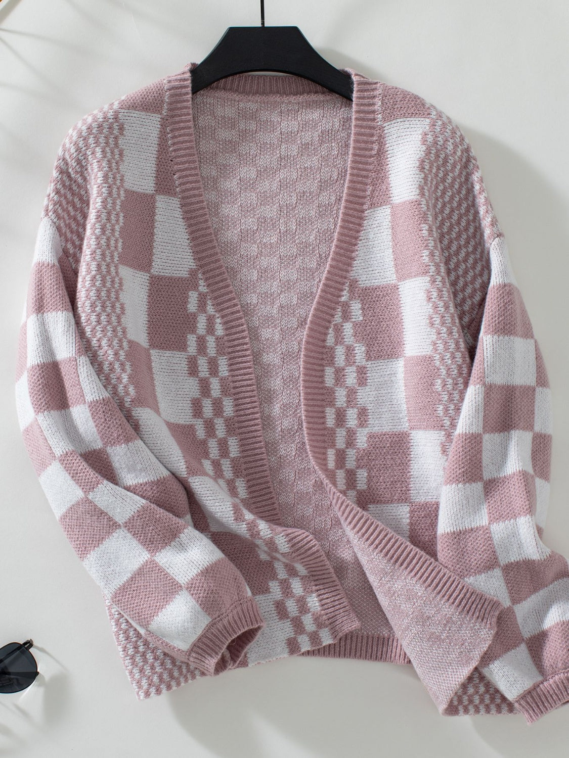 Dusty pink and white checkerboard knit open-front cardigan with textured sleeves.