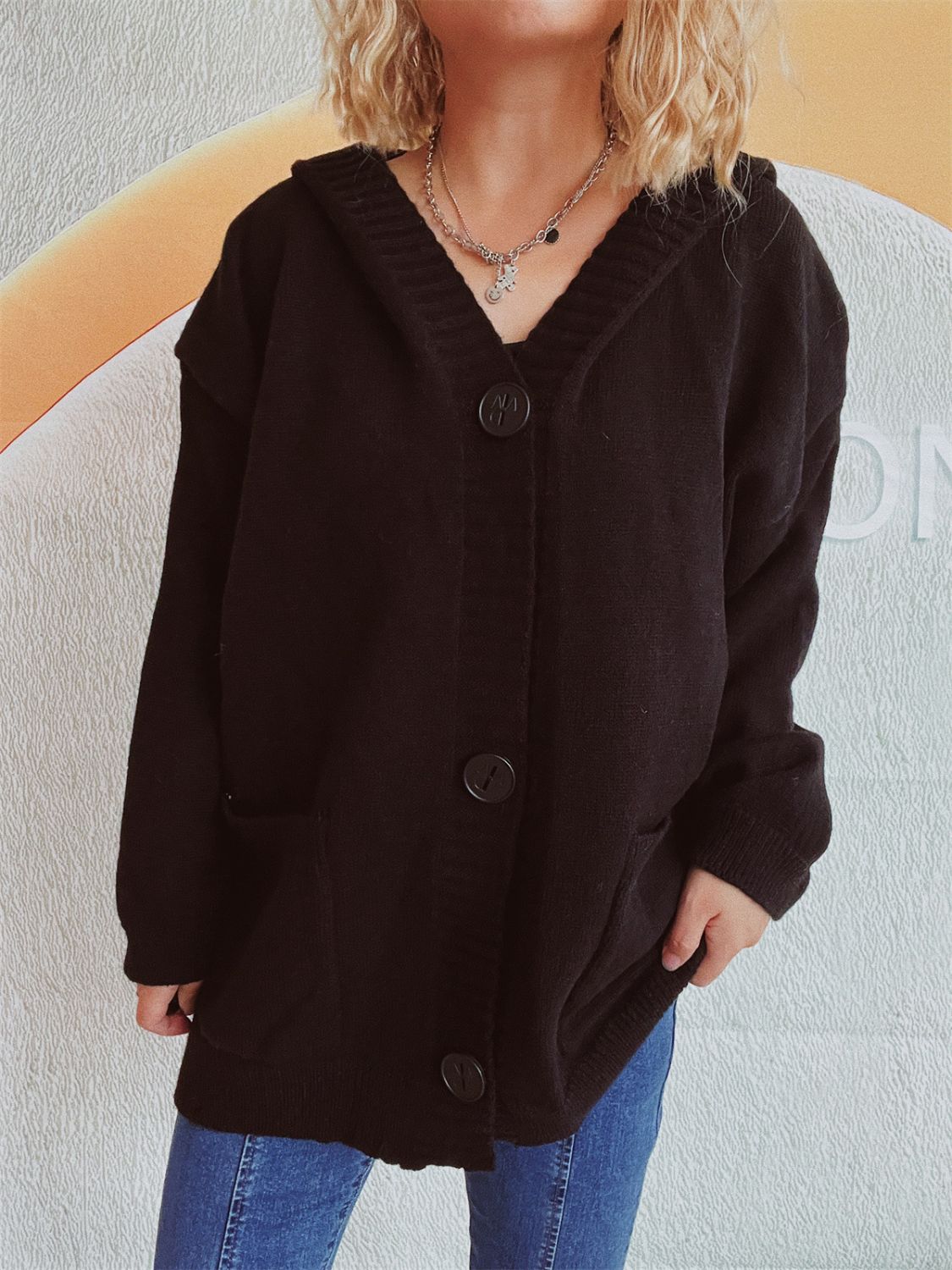 Black chunky knit hooded button-down cardigan with pockets and large buttons.