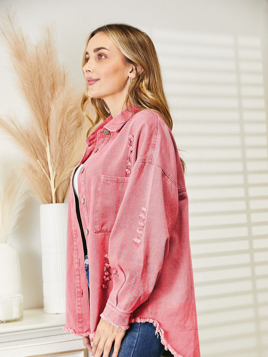 Distressed denim overshirt in blush pink with raw hem and button details.