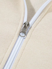Beige cotton zip-up jacket detail with silver zipper pull and white zipper tape.