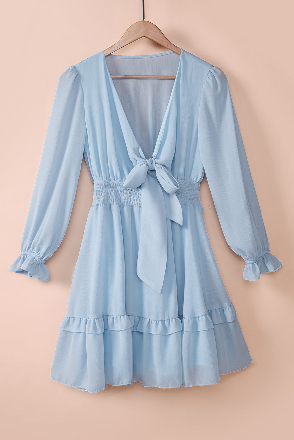 Sky blue mini dress with V-neck, bow-tie waist, smocked waist, and ruffled hem.