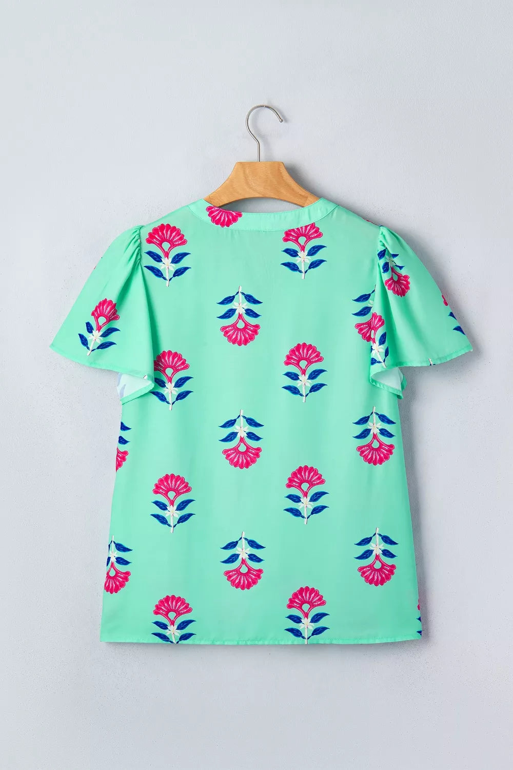 Mint green blouse with pink floral print, V-neck, and flutter sleeves.